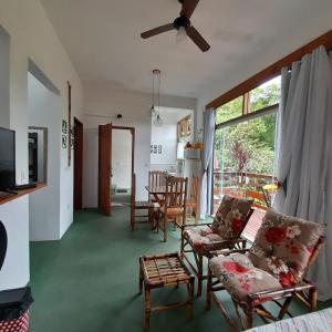 a living room with a couch and chairs and a table at La Casa Rozada Prumirim in Ubatuba