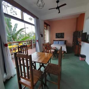 a dining room with a table and chairs and a bed at La Casa Rozada Prumirim in Ubatuba