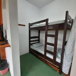 two bunk beds in a room with a green floor at La Casa Rozada Prumirim in Ubatuba