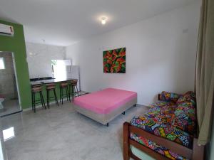 a room with a bed and a couch and a kitchen at Apartamentos Kairos in Ubatuba