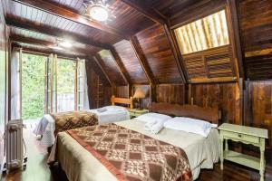 a bedroom with two beds in a room with wooden walls at Chalé inteiro completo a 5 min a pé do Capivari - Campos do Jordão in Campos do Jordão