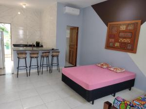a bedroom with a pink bed and a kitchen at Apartamentos Kairos in Ubatuba