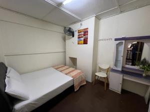 a small room with a bed and a table and a chair at De Cameron Guest House in Tanah Rata