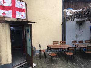 einen Tisch und Stühle vor einem Gebäude mit einer Flagge in der Unterkunft Kargi Youth Hostel in Tbilisi City