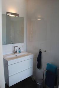 a white bathroom with a sink and a mirror at Sfeervol chalet midden in de natuur in Halle
