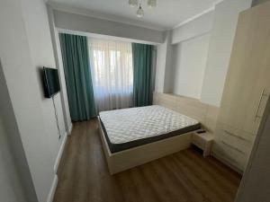 um pequeno quarto com uma cama e uma janela em Apartament de lux Pitesti centru em Piteşti