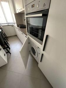 uma cozinha branca com um fogão e uma máquina de lavar louça em Apartament de lux Pitesti centru em Piteşti