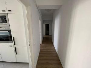 um corredor que leva a uma cozinha com armários brancos em Apartament de lux Pitesti centru em Piteşti