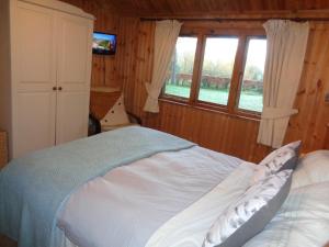 a bedroom with a bed and a window at Idyllic Log Cabin Near Stratford upon Avon in Stratford-upon-Avon