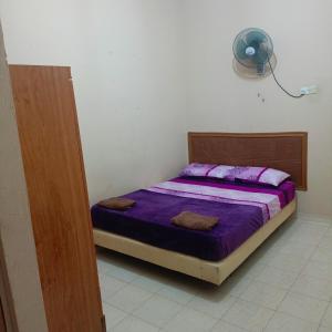 a bedroom with a bed with purple sheets and a fan at MieHomestay Bukit payong in Bukit Payong