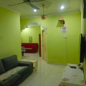 a living room with green walls and a couch at MieHomestay Bukit payong in Bukit Payong