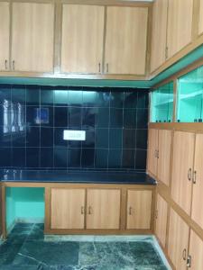 a kitchen with wooden cabinets and a black tiled wall at JK Home Stay in Tirupati