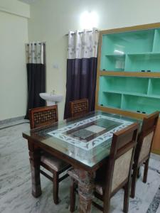 a dining room with a glass table and chairs at JK Home Stay in Tirupati