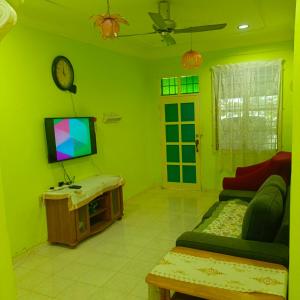 a green living room with a couch and a tv at MieHomestay Bukit payong in Bukit Payong
