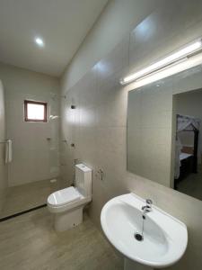 a bathroom with a sink and a toilet and a mirror at Maasai Koroga in Mombasa