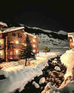 una cabaña de madera en la nieve por la noche en Exclusiva Cabaña en Vall D'Incles - Pistas de Ski & Vistas al Valle - Parking Incluido, en Canillo