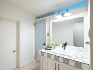 La salle de bains est pourvue d'un lavabo et d'un miroir. dans l'établissement Yama'oto - Nature Luxury Stay, à Motobu