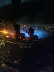 a couple drinking wine in a hot tub at night at Domek Viking in Gródek Nad Dunajcem