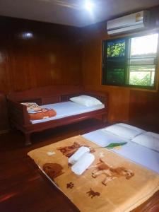 a room with two beds and a window and a table at บ้านสวนชนะจน in Fang