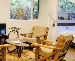 a living room with chairs and a bed and a table at Yama'oto - Nature Luxury Stay in Motobu
