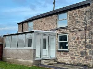 an extension to a stone house with white doors at Castle Keep - Traditional Welsh Cottage in Llandudno Junction