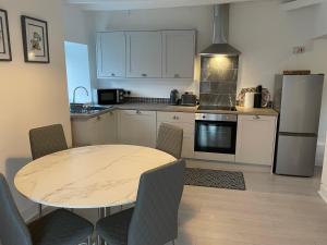 une cuisine avec une table avec des chaises et un réfrigérateur dans l'établissement Sarn Y Mynach - Traditional Welsh Cottage, à Llandudno Junction