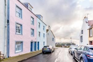 a street with two cars parked in front of buildings at Pass the Keys The Lofthouse St Monans in Anstruther