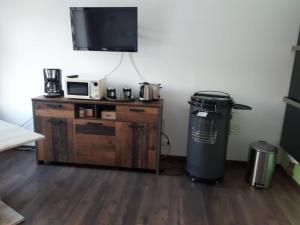 a room with a trash can and a microwave and a television at Ferienwohnung am Schwimmteich in Lachendorf