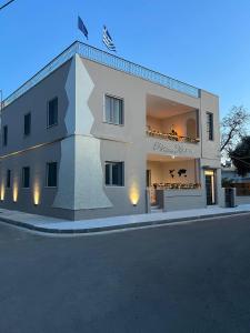 un grand bâtiment blanc sur le côté d'une rue dans l'établissement Elefsinian Mysteries Apartments, à Elefsina