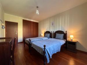 豐沙爾的住宿－Plaza near Forum Madeira，一间卧室配有两张带蓝色床单的床和两盏灯。
