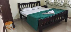 a bed with a green blanket and white shoes on it at Manjippuzha Nature Space in Alleppey
