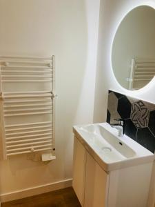 La salle de bains blanche est pourvue d'un lavabo et d'un miroir. dans l'établissement Le gîte de Mireloup, à Plerguer