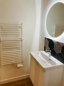 a white bathroom with a sink and a mirror at Le gîte de Mireloup in Plerguer
