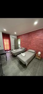 Habitación con 2 camas y pared roja. en Etna &Vita, en San Giovanni la Punta