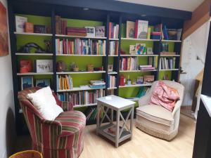 una habitación con 2 sillas y una estantería con libros en Nature & bien-être, en Étival-Clairefontaine
