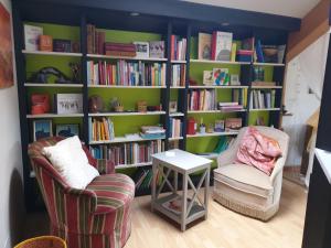 a room with two chairs and a book shelf with books at Nature & bien-être - À l'étage avec 2 chambres in Étival-Clairefontaine