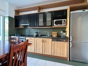 a kitchen with wooden cabinets and a stainless steel refrigerator at Plaza near Forum Madeira in Funchal