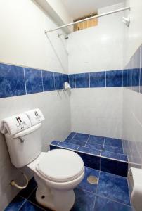 baño azul y blanco con aseo y azulejos azules en Hotel Italia I, en Chiclayo