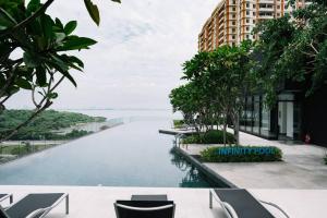 JelutongにあるNEW Infinity Pool Seaview 3Bedrooms 2Carparks 262のスイミングプール(椅子付)と建物の景色を望めます。