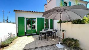 uma mesa com um guarda-chuva em frente a uma casa em Petite location dans résidence avec piscine et terrains de tennis em La Couarde-sur-Mer