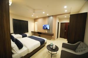 a hotel room with two beds and a television at Maruti Group of Hotels - The Shivam in Nāthdwāra