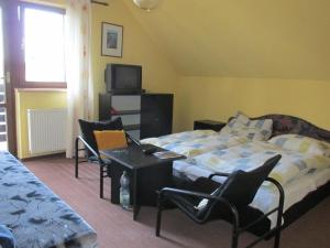 a bedroom with a bed and chairs and a television at Dum Eva in Janske Lazne