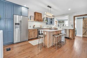 a kitchen with a refrigerator and bar stools in it at Underground Railroad 3 Bedroom Farmhouse in Kennett Square