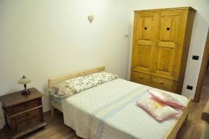 een kleine slaapkamer met een bed en een houten kast bij Vista da Sogno, Casa di Montagna per il Tuo Relax in Villadossola