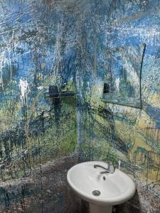 a bathroom with a sink and a painting on the wall at Mestia Eco Huts in Mestia