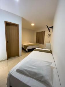 a hotel room with a bed and a bedroom with a door at Recanto Bromélias in Camburi