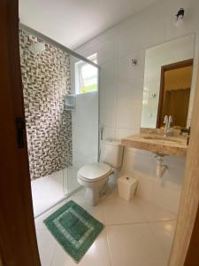 a bathroom with a toilet and a sink and a mirror at Recanto Bromélias in Camburi