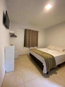 1 dormitorio con 1 cama y TV de pantalla plana en Recanto Bromélias en Camburi