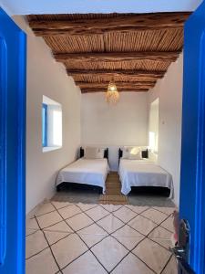 Dos camas en una habitación con techo de madera. en Dar Isma : Une maison sur océan, en Wassane