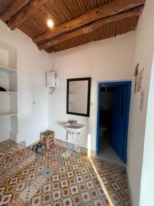 a bedroom with a blue door and a sink at Dar Isma : Une maison sur océan in Wassane